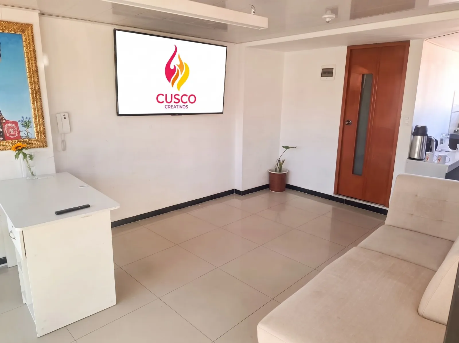 Recepción de la oficina de Cusco Creativos en Cusco, con el logo de la agencia en la pantalla