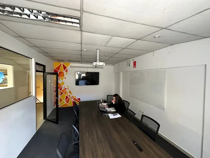Sala de reuniones de Cusco Creativos en Cusco, con mesa larga, proyector, TV y pizarra