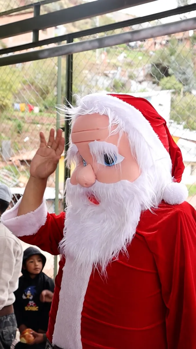 Papá Noel saluda con la mano a los niños en la actividad navideña de Cusco Creativos en Santiago