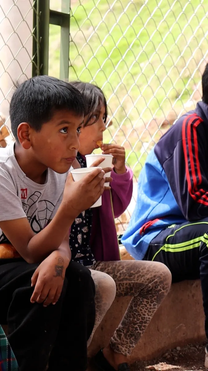 Niños toman una bebida caliente con pan durante la Navidad 2023 de Cusco Creativos