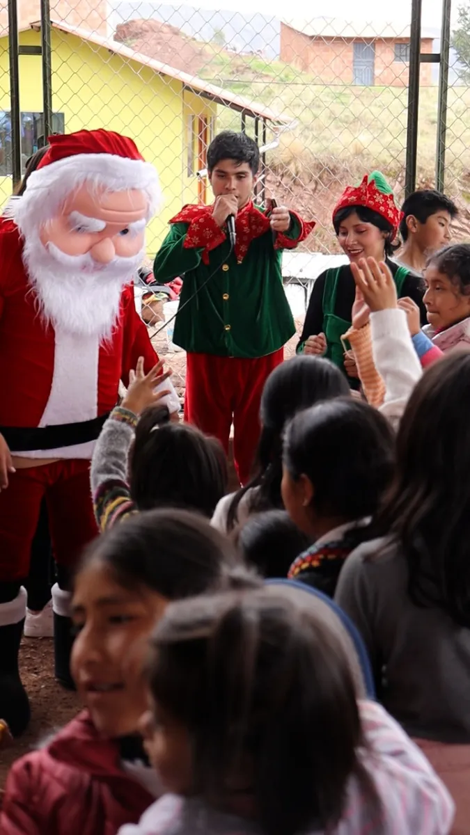 Papá Noel y un duende rodeados de niños en la actividad social de Cusco Creativos en Santiago