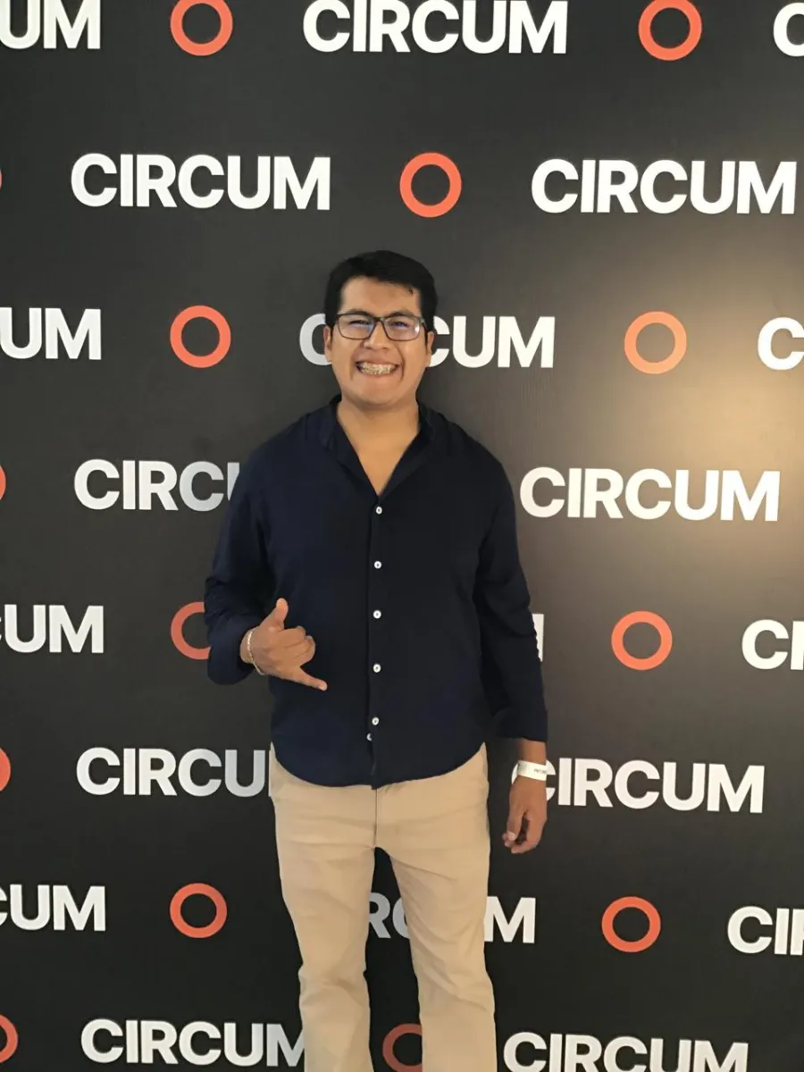 Paul Pumalloclla en un evento, frente a un panel con logos