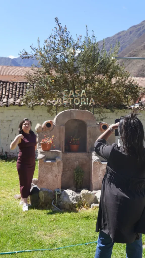 Sesión fotográfica en el hotel Casa Victoria de Cusco: una fotógrafa retrata a una mujer junto al letrero «Casa Victoria», en el patio del hotel